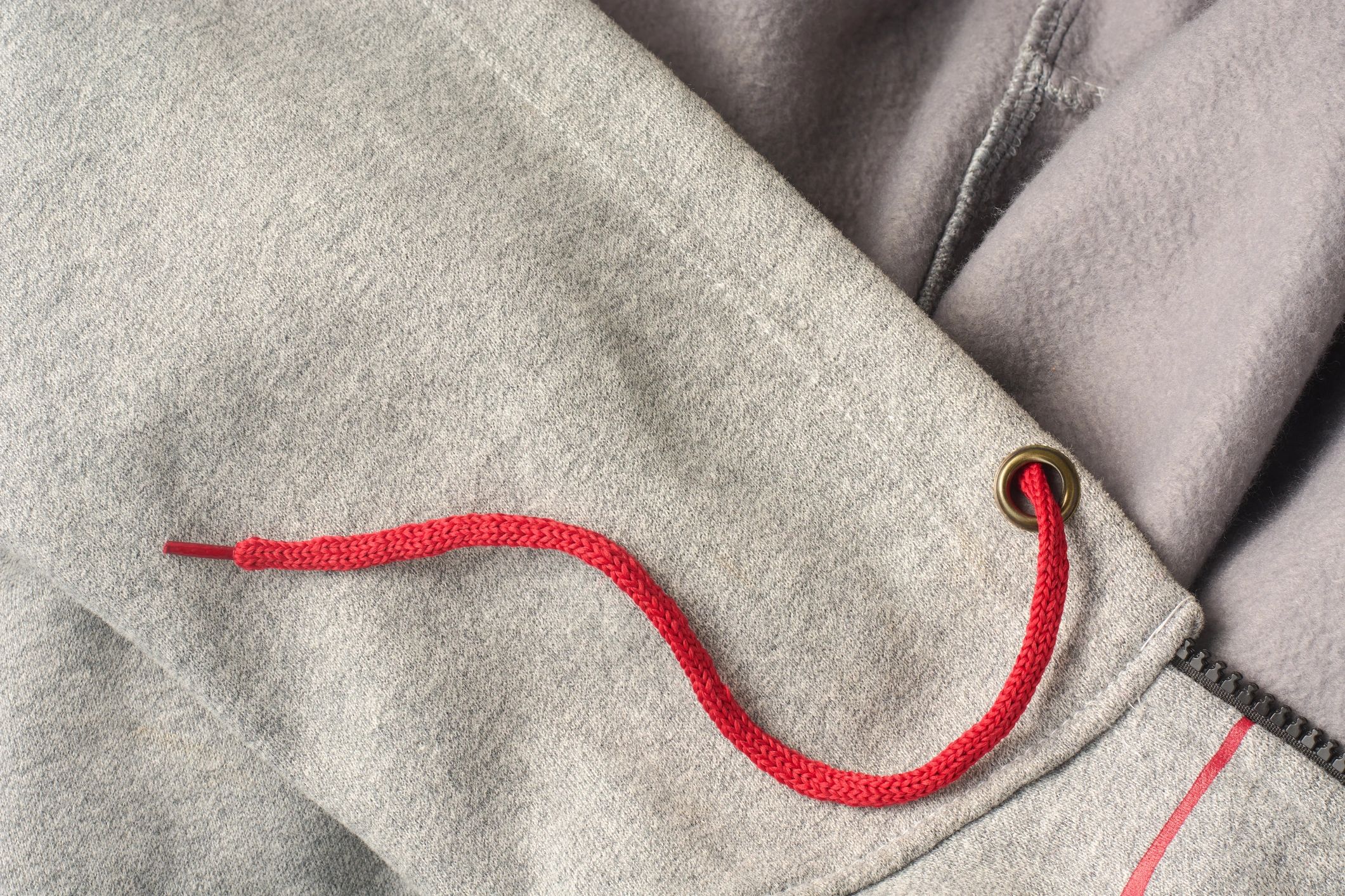Close-up texture of a gray hoodie with red drawstring